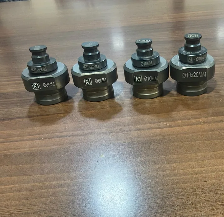 Four busbar dies laser marked Ø6, Ø8, Ø10 and Ø10×20 mm with the Mahavir M, on a workbench.