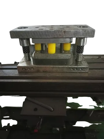 A press tool die set with guide pillars, mounted on a machine bed.